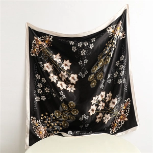 Detailed close-up of a floral silk scarf with lily patterns and premium beige piping edge