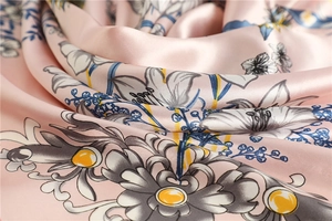 Macro detail of silky floral scarf showing smooth satin texture and elegant lily print