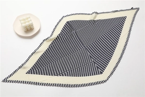 Detail of pleated silk scarf featuring geometric black stripes on creamy white fabric
