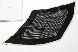Close-up of plissé pleated silk scarf with black and white geometric diamond patterns