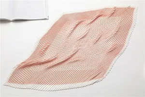 Detailed close-up of pleated pink and white geometric silk scarf with wavy texture
