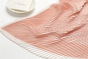 Macro detail of pleated silk scarf featuring orange-pink stripe pattern and fine texture