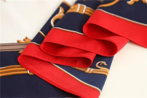 Close-up of luxury silk scarf showing detailed horse carriage and chain patterns