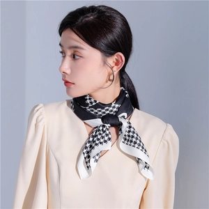 Dettaglio di un foulard in seta pied-de-poule bianco e nero annodato con eleganza