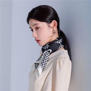 Dettaglio di un foulard in seta pied-de-poule bianco e nero indossato come elegante sciarpa