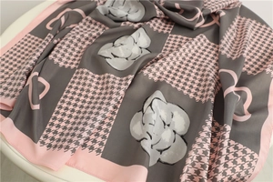 Dettaglio di un foulard in seta con motivi pied de poule e fiori di camelia in rosa e grigio