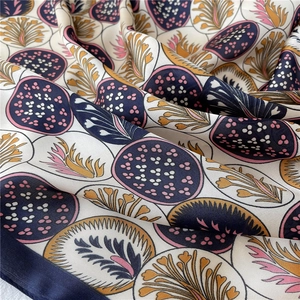 Gros plan du foulard en soie montrant les motifs de feuilles et le tissu satiné
