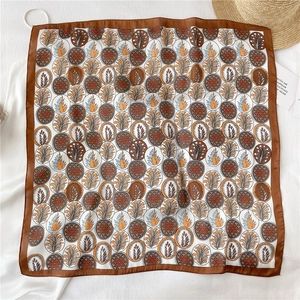 Détail d'un foulard carré effet soie avec motifs de feuilles et imprimés rétro chic