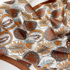 Gros plan d'un foulard en soie avec motifs de plumes abstraits et texture soyeuse