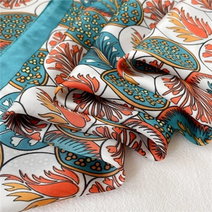 Détail macro d'un foulard en soie avec motifs floraux vintage et bords roulés verts