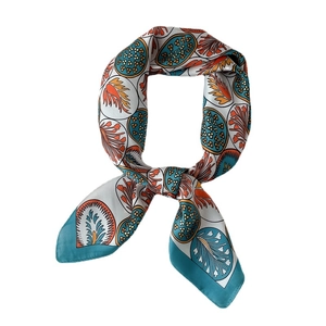 Foulard soyeux aux motifs de feuilles et pois, noué avec style sur fond blanc