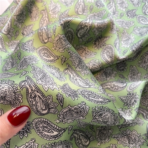 Détail du foulard en soie verte avec motif cachemire noir et blanc et texture soyeuse