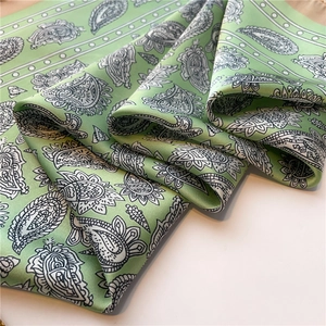 Détail d'un foulard en soie vert clair avec motif cachemire classique noir et blanc