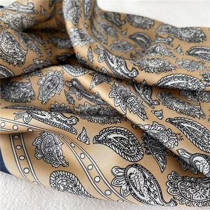 Détail d'un foulard en satin à motif paisley avec une texture soyeuse et brillante