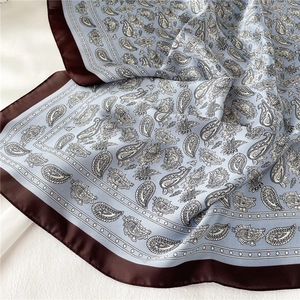 Détail du motif paisley sur un foulard en soie synthétique bleu clair et marron