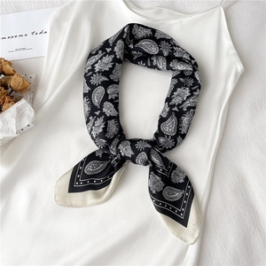 Détail macro du foulard en soie avec motif paisley et bordures élégantes noir et blanc