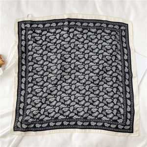 Détail d'un foulard carré en soie à motif paisley avec une bordure crème élégante