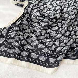 Gros plan détaillé du motif cachemire noir sur un foulard carré en satin de soie douce