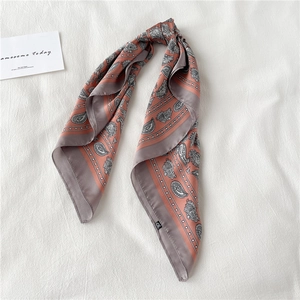 Détail d'un foulard en soie à motif paisley corail et gris aux imprimés élégants et raffinés