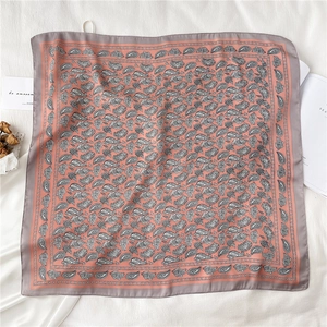 Détails du motif paisley sur un foulard carré en soie aux tons rose Morandi et gris