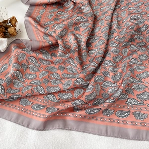 Détail du foulard en soie à motif paisley rose avec texture satinée et bords cousus