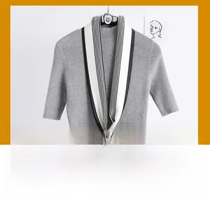 Détail d'un pull en tricot gris avec un foulard en soie étroit à rayures noires et blanches