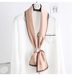 Détail d'un foulard en soie rayé rose champagne sur le col d'une chemise blanche