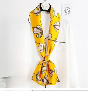 Detail of a yellow floral silk scarf tied elegantly on a white shirt as a luxury accessory