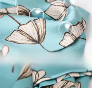 Macro detail of faux silk scarf fabric showing blue ginkgo leaf pattern and texture