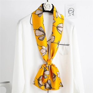 Narrow silk scarf with yellow ginkgo print tied to white satin shirt collar