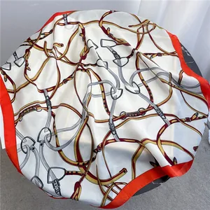 Detail of silk square scarf showing luxury equestrian belt and chain prints with red border