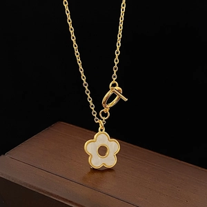 Detail der goldenen Blumenkette mit weißer Muschel und T-Verschluss auf Holz