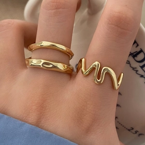 Minimalist irregular layered gold ring set featuring polished wavy designs on female hand