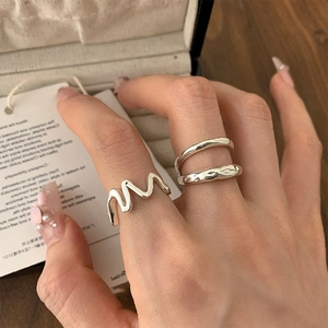 Close-up of irregular wave and double-layered silver rings on hand with creative nail art