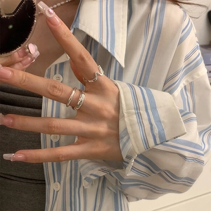 Detailed view of irregular silver ring set featuring minimalist wave and textured styles