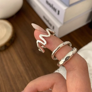 Close-up of three minimalist silver rings with smooth and irregular textured surfaces
