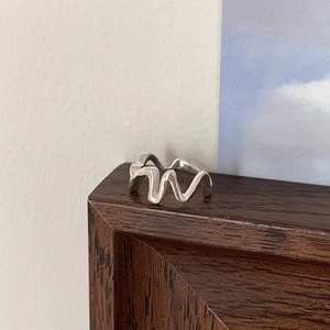 Macro shot of silver irregular wavy ring with modern minimalist design and polished finish