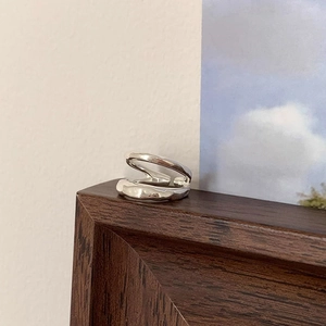 Close-up of irregular liquid-metal style silver ring on a wooden frame background