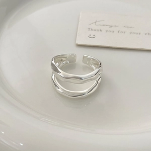 Close-up of irregular silver double-layer wavy ring on a white ceramic tray