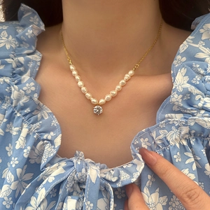 Close-up of vintage baroque freshwater pearl necklace with zircon pendant on a model