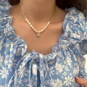 Close-up of vintage baroque pearl necklace with a sparkling zircon pendant on a model