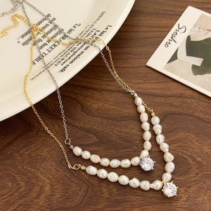 Detailed close-up of Baroque pearl necklaces with zircon pendants in gold and silver finish