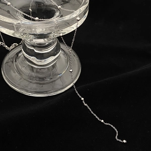 Détail d'un collier à billes argentées avec perles polies sur fond en velours noir