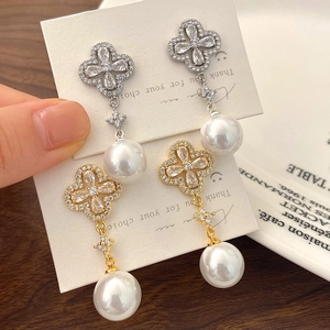 Detailed view of four-leaf clover stud earrings with cubic zirconia and large pearl drop