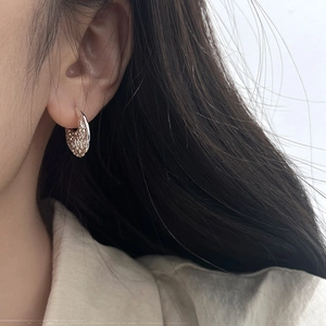 Gros plan de boucles d'oreilles créoles argentées à texture martelée portée