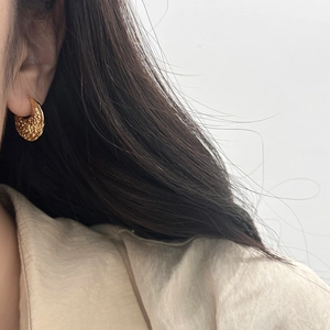 Détail de créoles dorées vintage avec texture martelée style lave et design épais