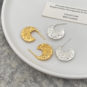 Détail des boucles d'oreilles en C avec texture de lave irrégulière en coloris or et argent