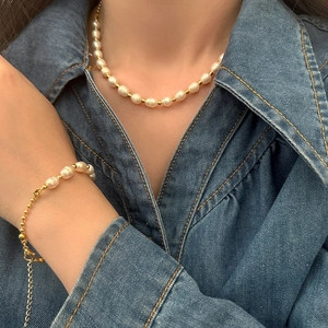 Detail view of natural freshwater pearl necklace and bracelet with gold beads on denim