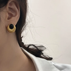 Close-up of French vintage gold ribbed earrings with oval black stone on model