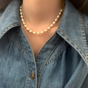 Elegant natural freshwater pearl necklace with gold metal beads on a denim shirt